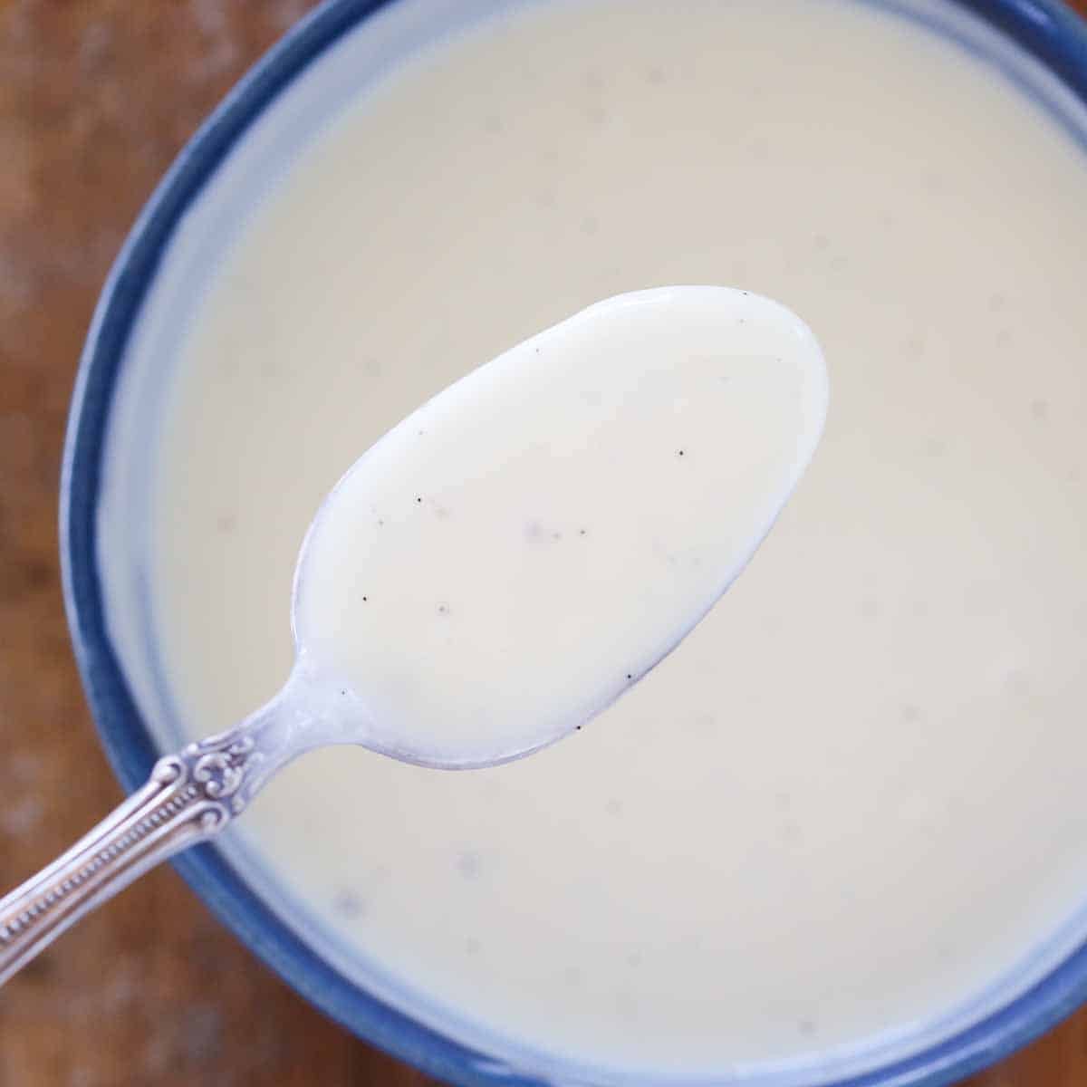 creme anglaise on spoon over bowl.