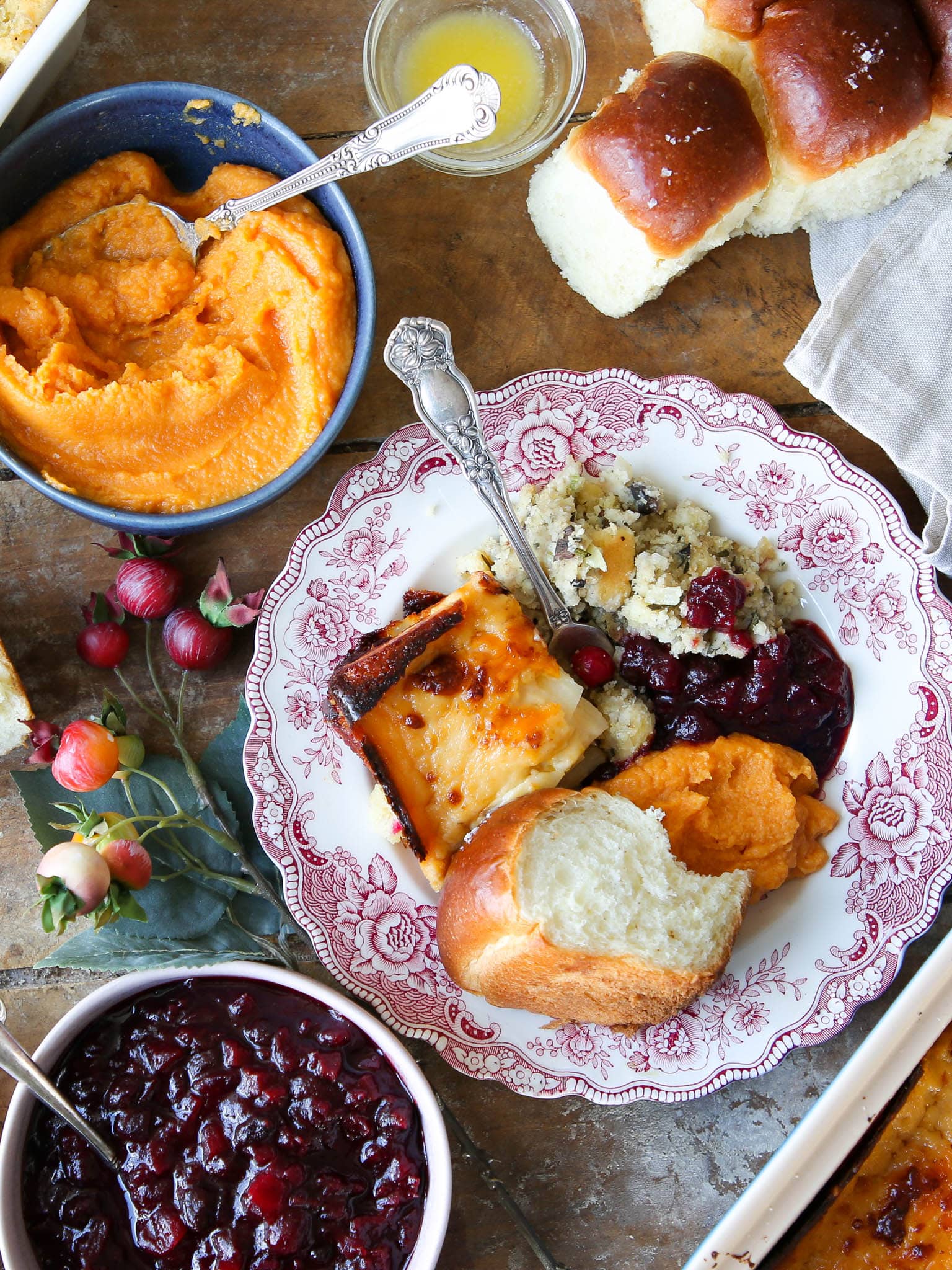 traditional thanksgiving dinner on pink china plate with side dishes surrounding.