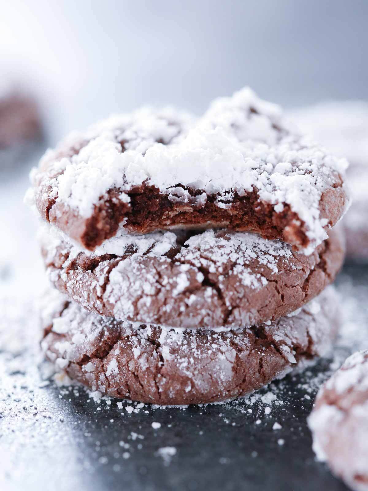 Easy chocolate dessert of chocolate crinkle cookies in a stack with the top one bitten.