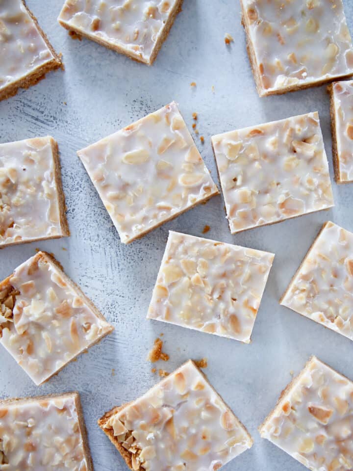 Sliced crispy almond square cookies over a light blue background.