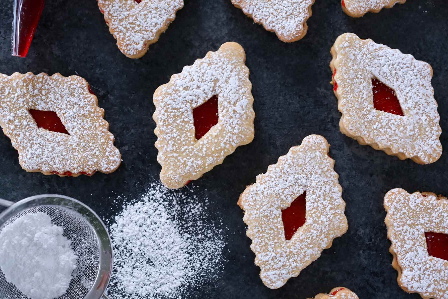 raspberry linzer cookies cut in diamonds on grey background.