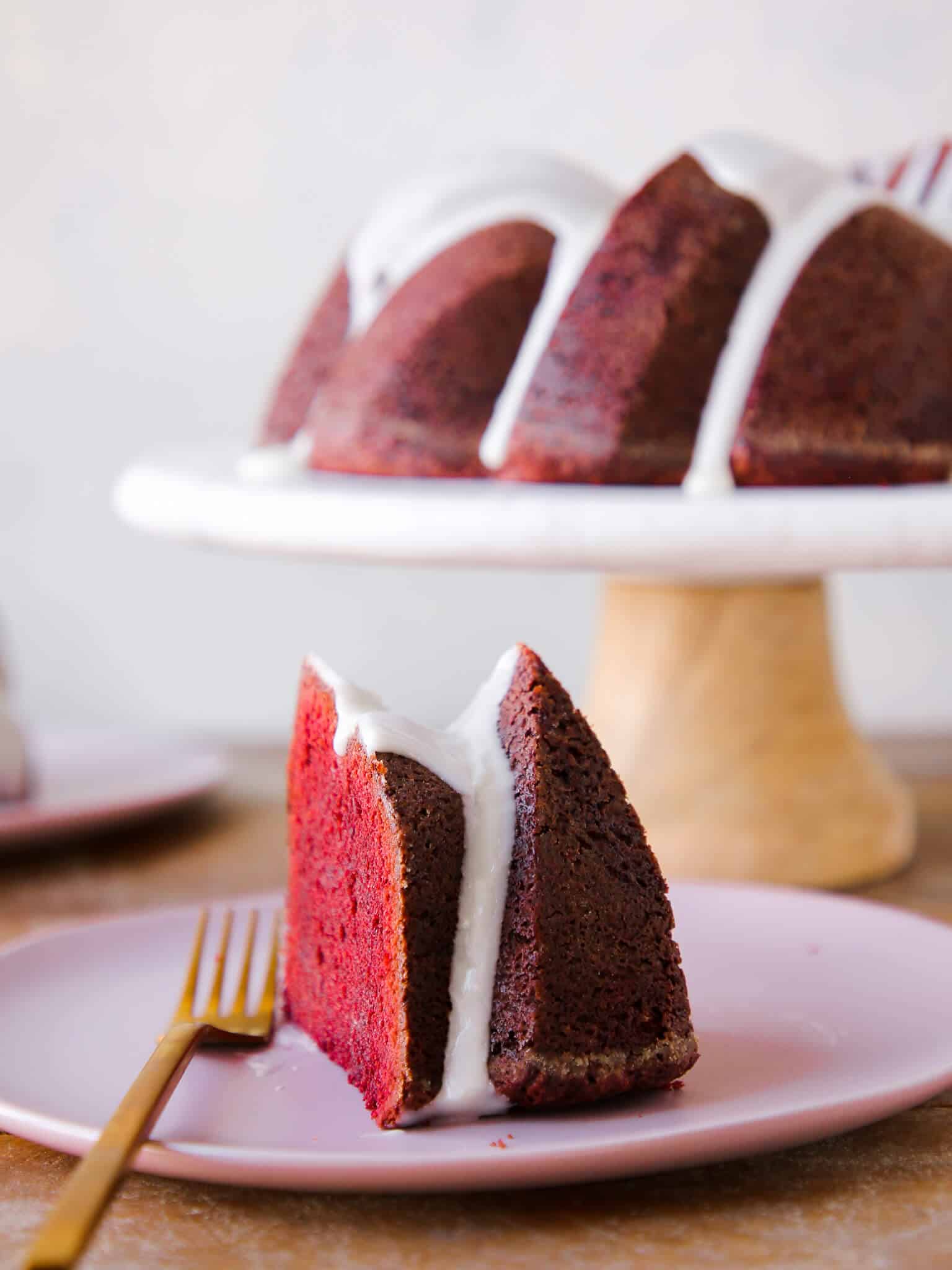 Red Velvet Pound Cake Cream Cheese Glaze slice with whole cake in background Valentine's Day Desserts