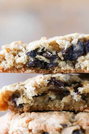 Oatmeal raisin cookies stacked against a light brown background.