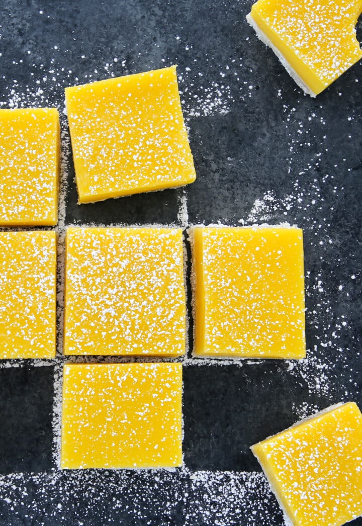 Lemon Bars Confectioners Sugar Scattered on Grey Board