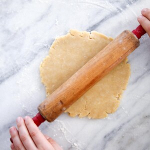 Old Fashioned Almond Pie Crust on marble surface with antique rolling pin