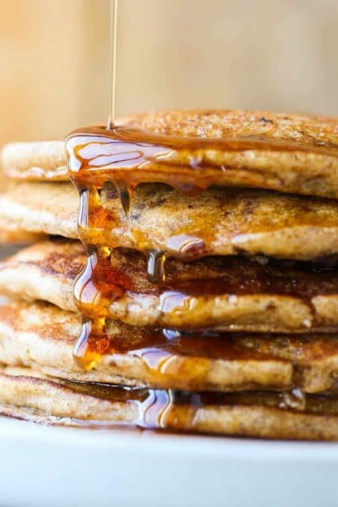 Whole wheat pancakes stacked with maple syrup