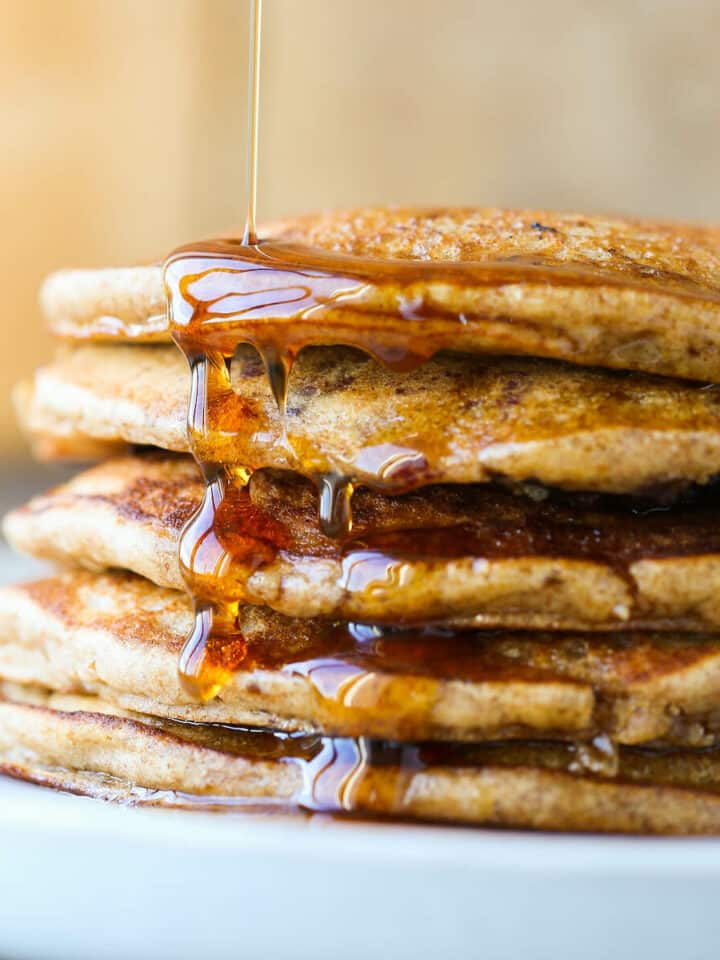 Whole wheat pancakes stacked with maple syrup