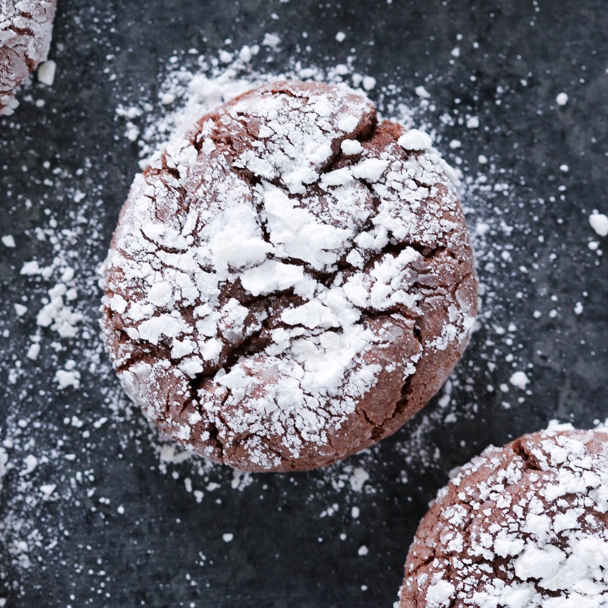 Easy crackle cookies with powdered sugar on black surface