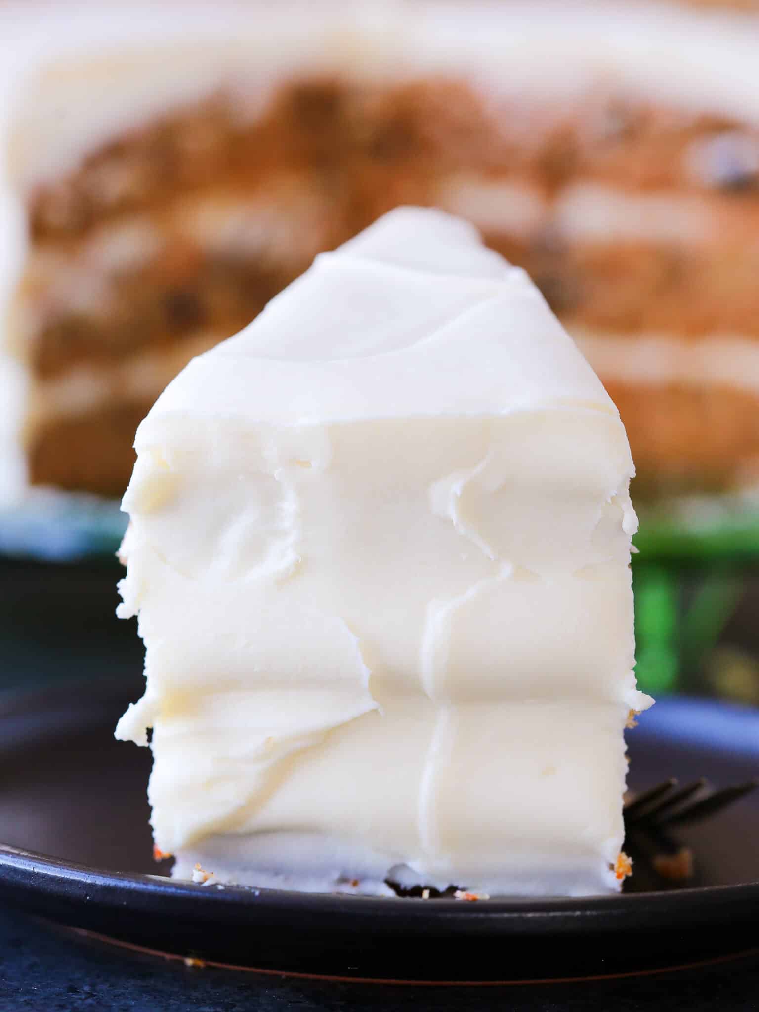 a slice of smoothly frosted carrot cake.