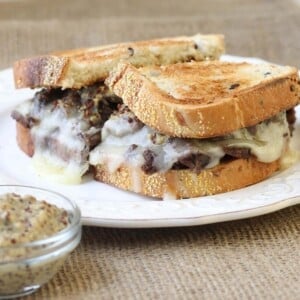 Roast beef melt with swiss cheese melting down the sides.