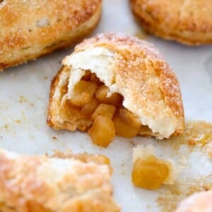 hand pie opened on baking sheet with apple filling spilling out.