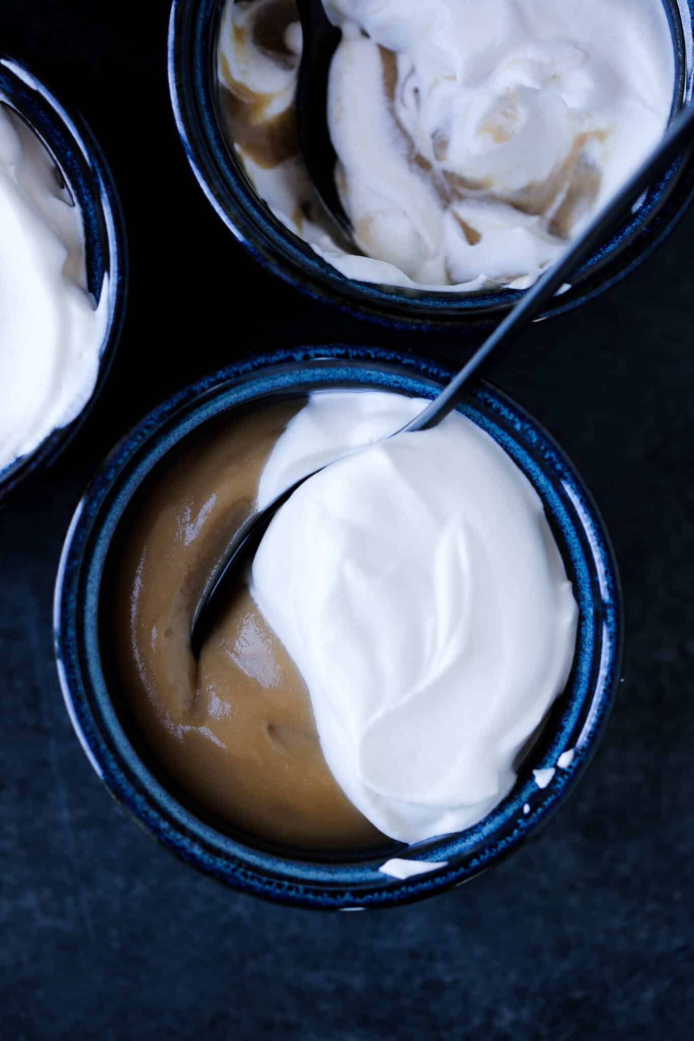 Butterscotch pudding in serving bowls against a dark background.