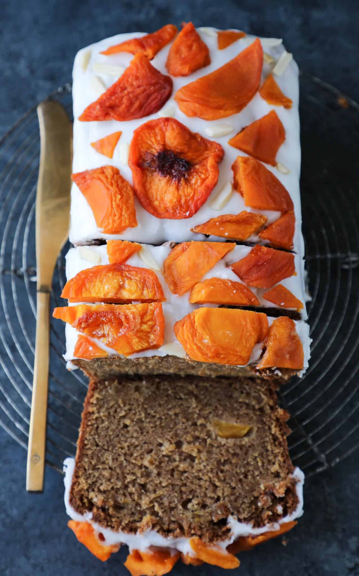 sliced peach loaf cake with white icing. 