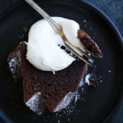 A slice of chocolate pound cake with whipped cream dolloped on top.