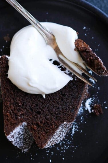 A slice of chocolate pound cake with whipped cream dolloped on top.