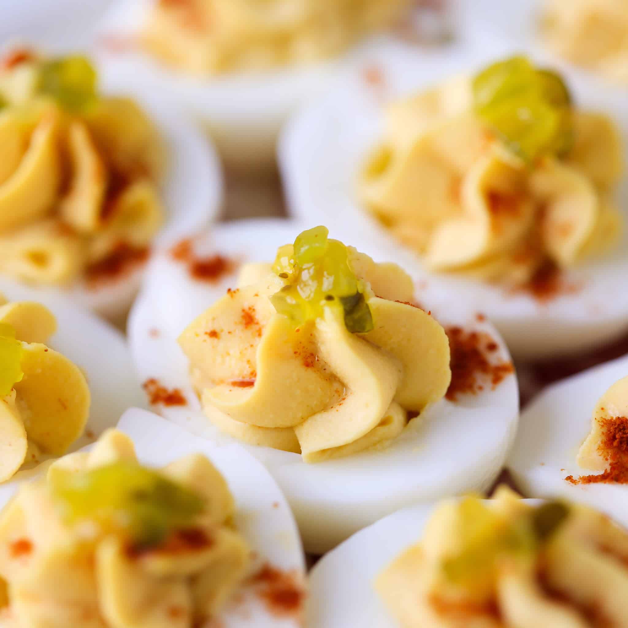 Deviled eggs topped with green relish and paprika.