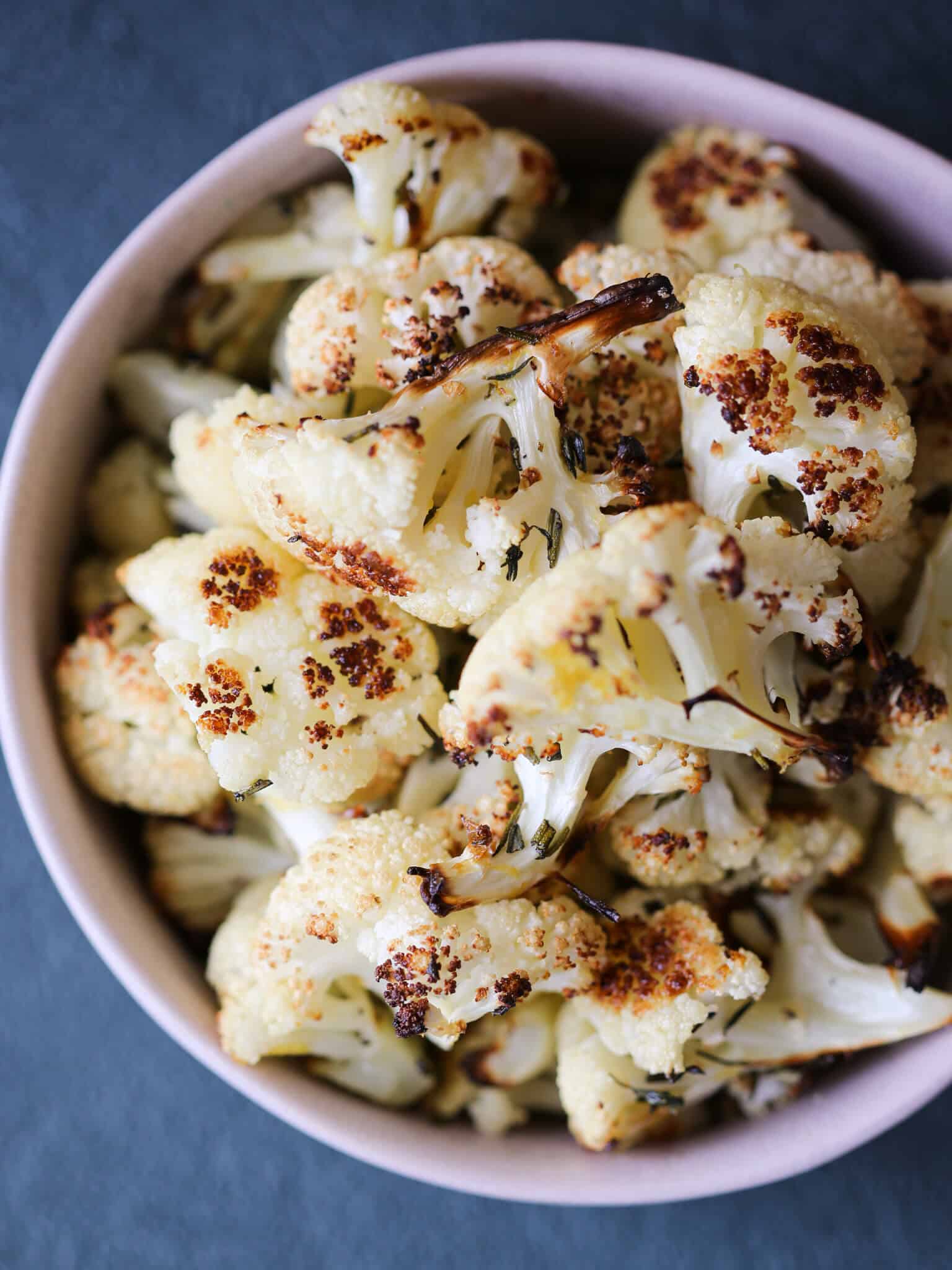 Easy Rosemary Lemon Roasted Cauliflower pink bowl on a green surface