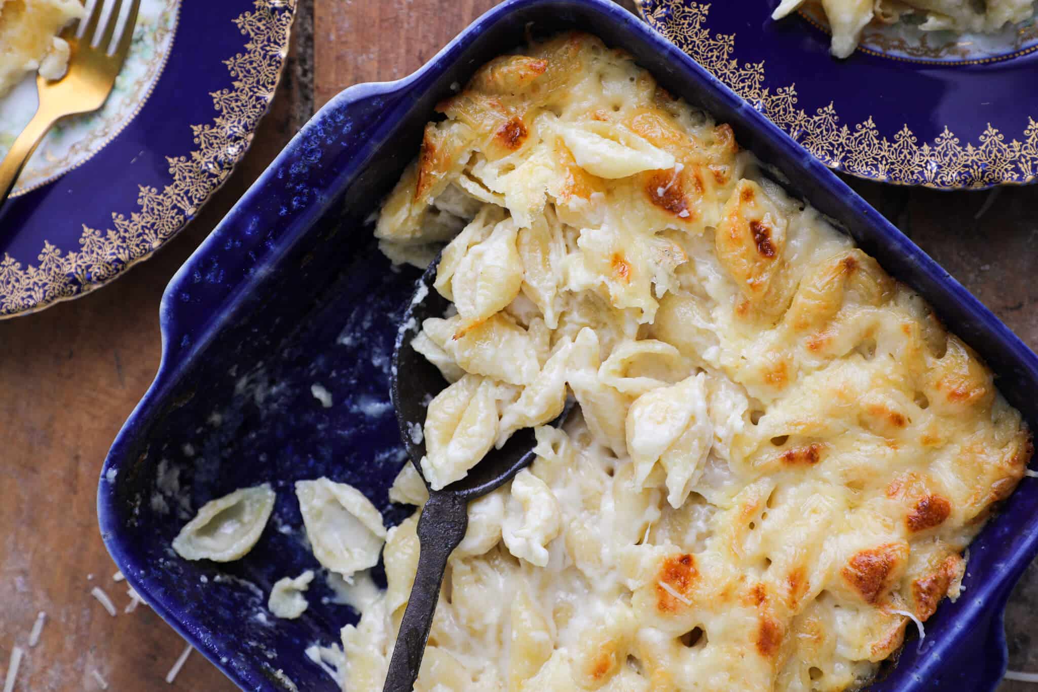 An almost full baking dish of white mac and cheese on a wood slate counter.