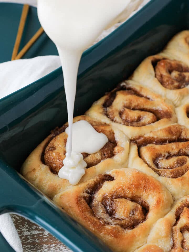 The best cinnamon rolls glaze pouring over baked rolls