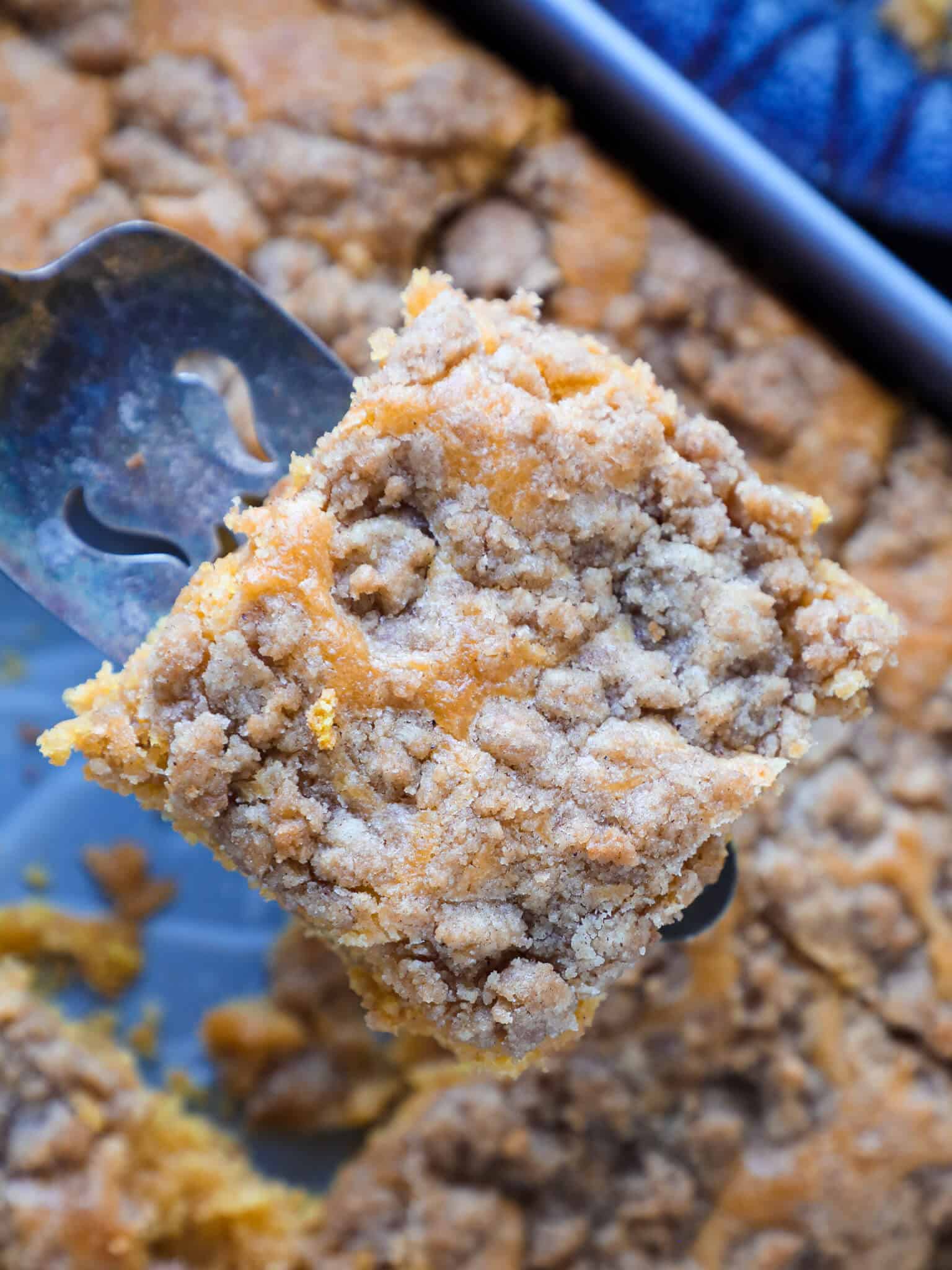 pumpkin coffee cake on cake server over top of cake in dish.