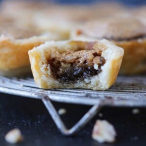 Pecan tassie on a dark background with flaky layered crust.