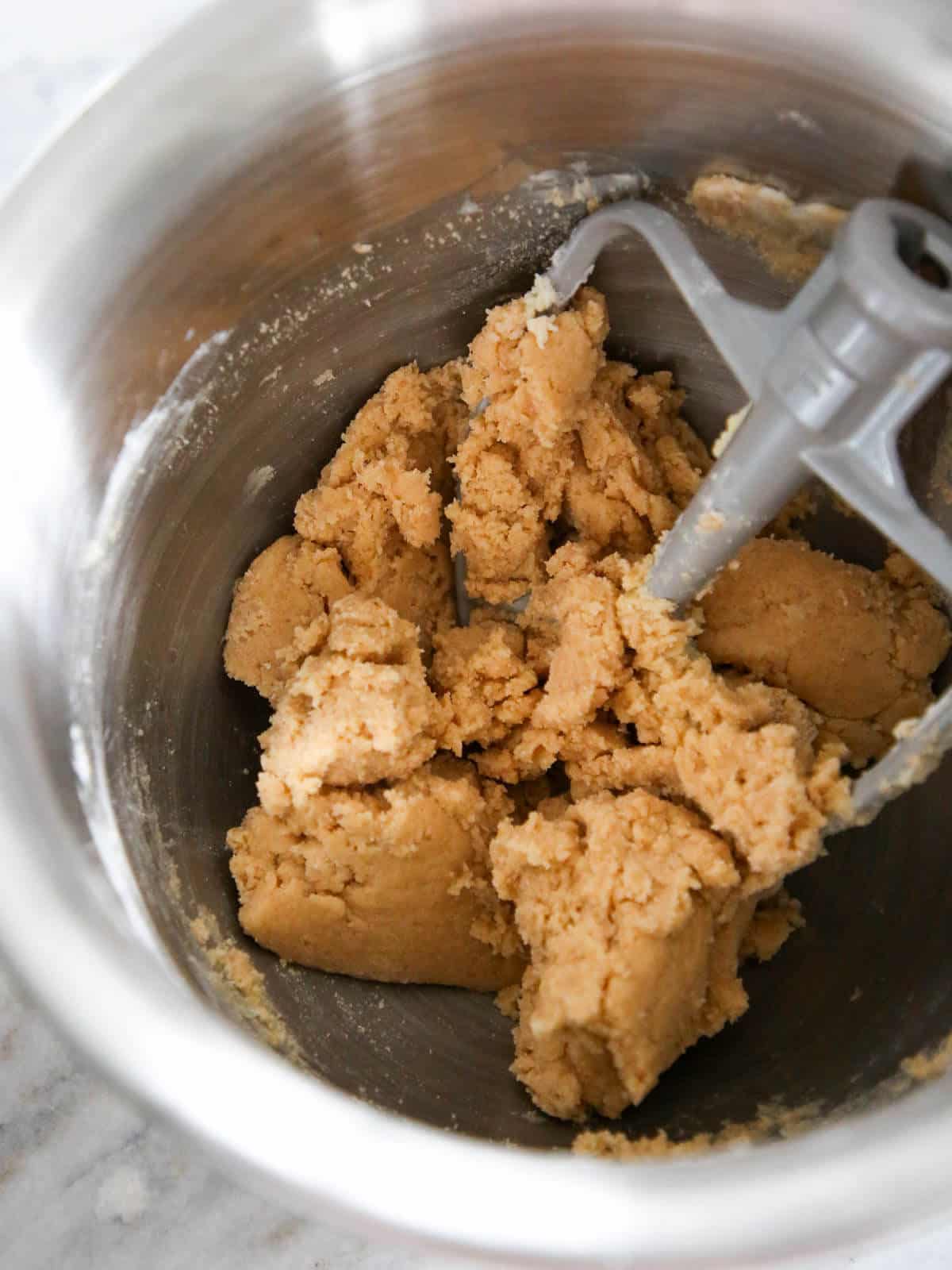 Cookie batter in a silver stand mixer bowl.