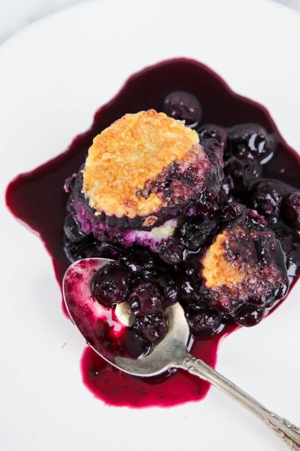 blueberry cobbler on white plate with vintage spoon.