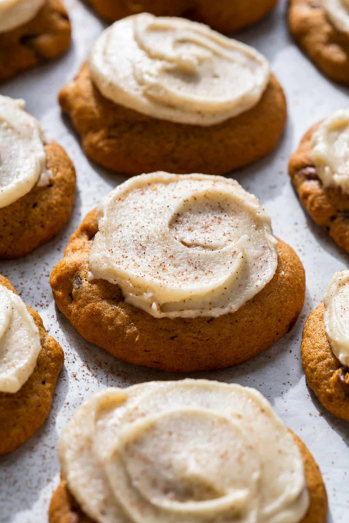 pumpkin cookies with white icing on parchment.