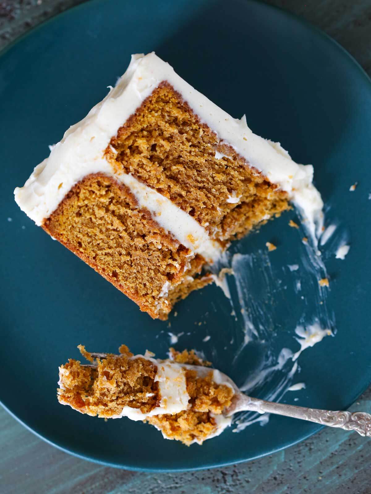 A fork filled with pumpkin cake from a plated slice.