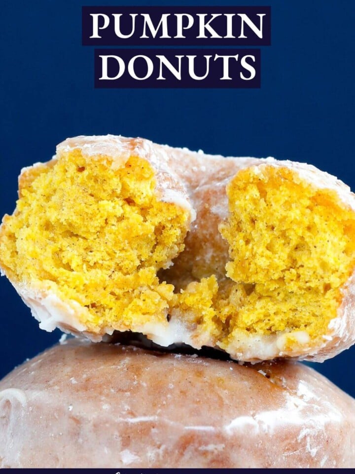 A pumpkin donut sliced in half to see a perfect orange crumb inside.