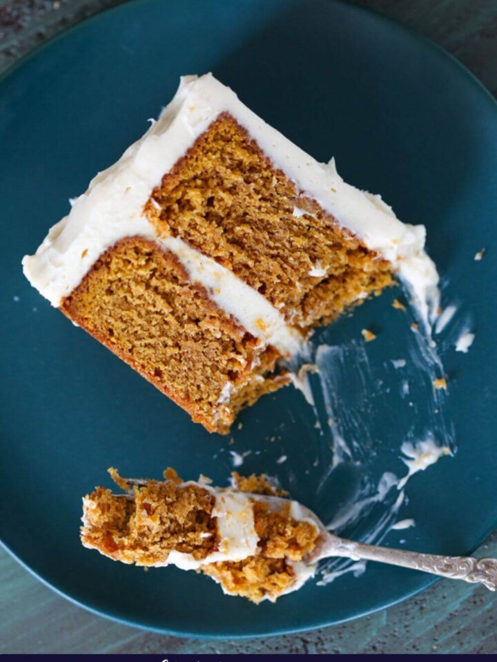 A forkful of pumpkin spice layer cake against a blue plate.