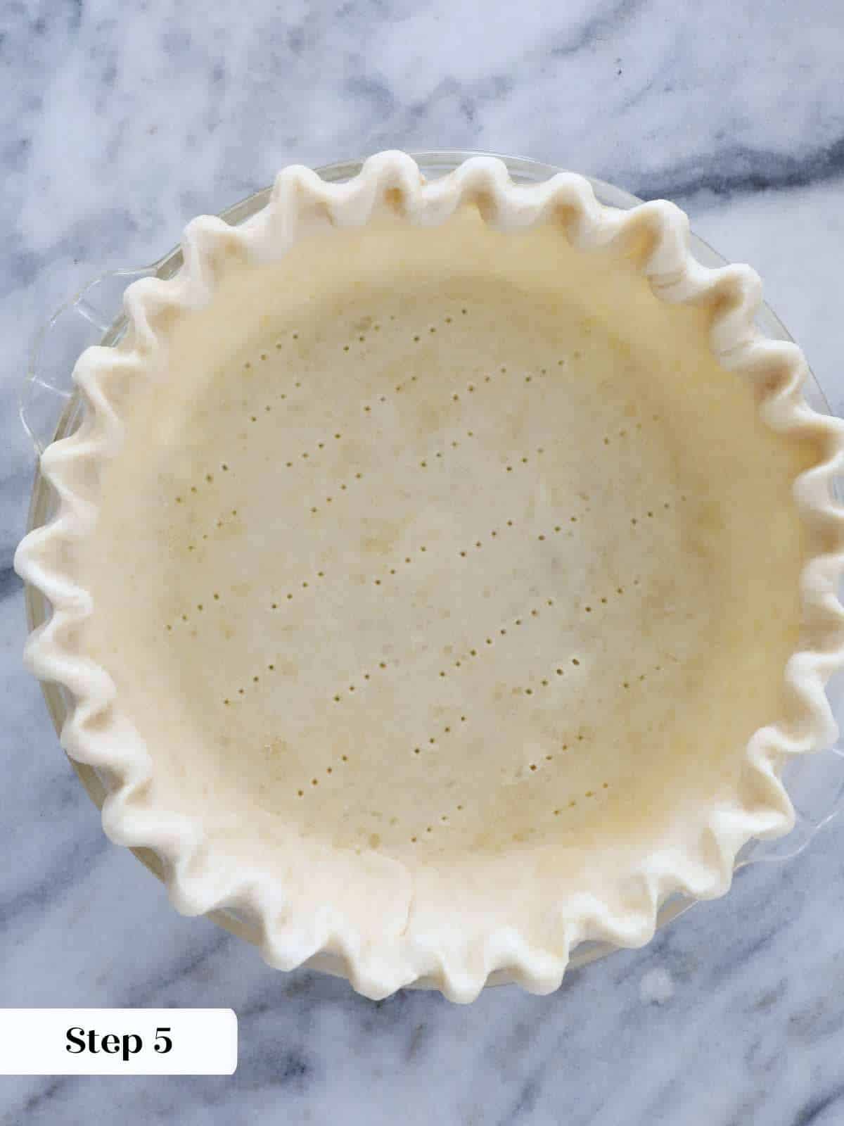 lined fluted docked unbaked pie crust in tin.