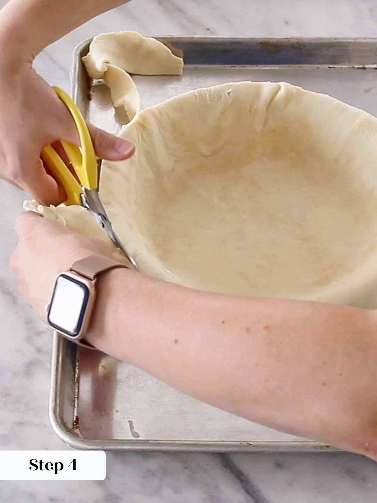 trimming excess dough from pie with scissors.