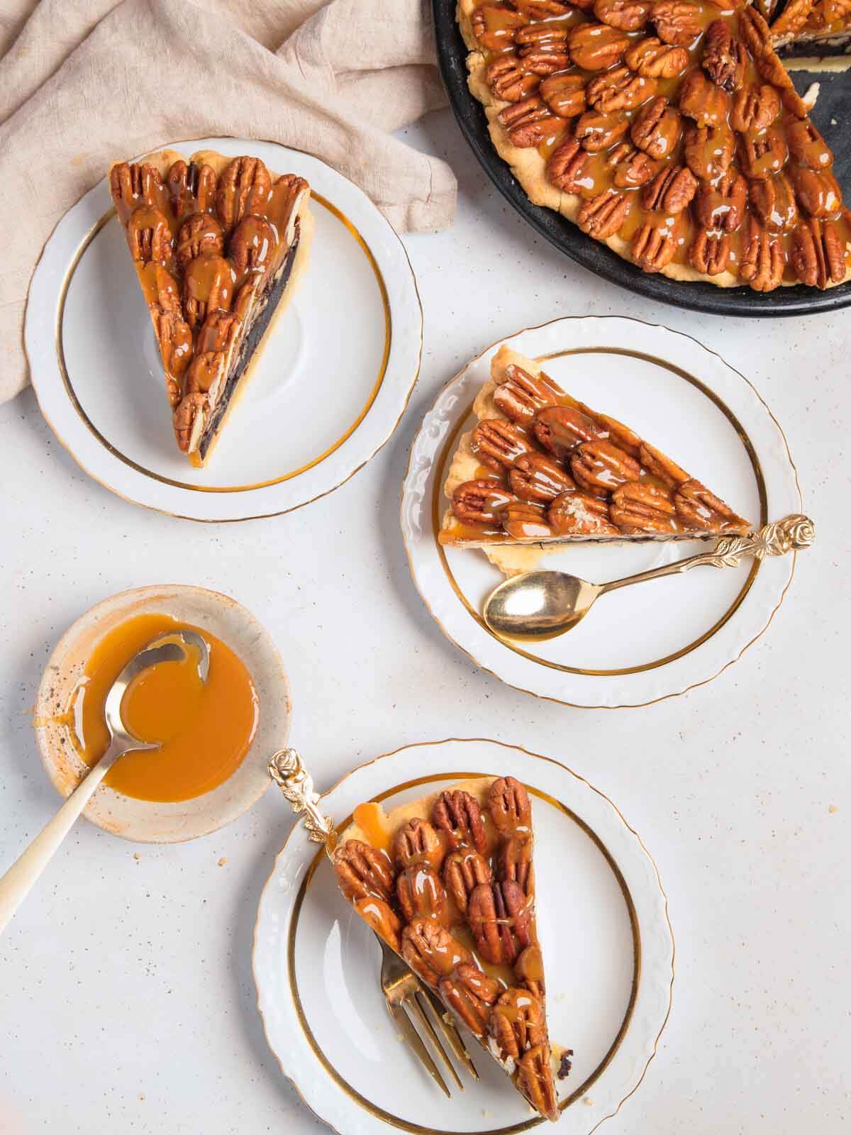 Three slices of chocolate pecan pie on a white background.