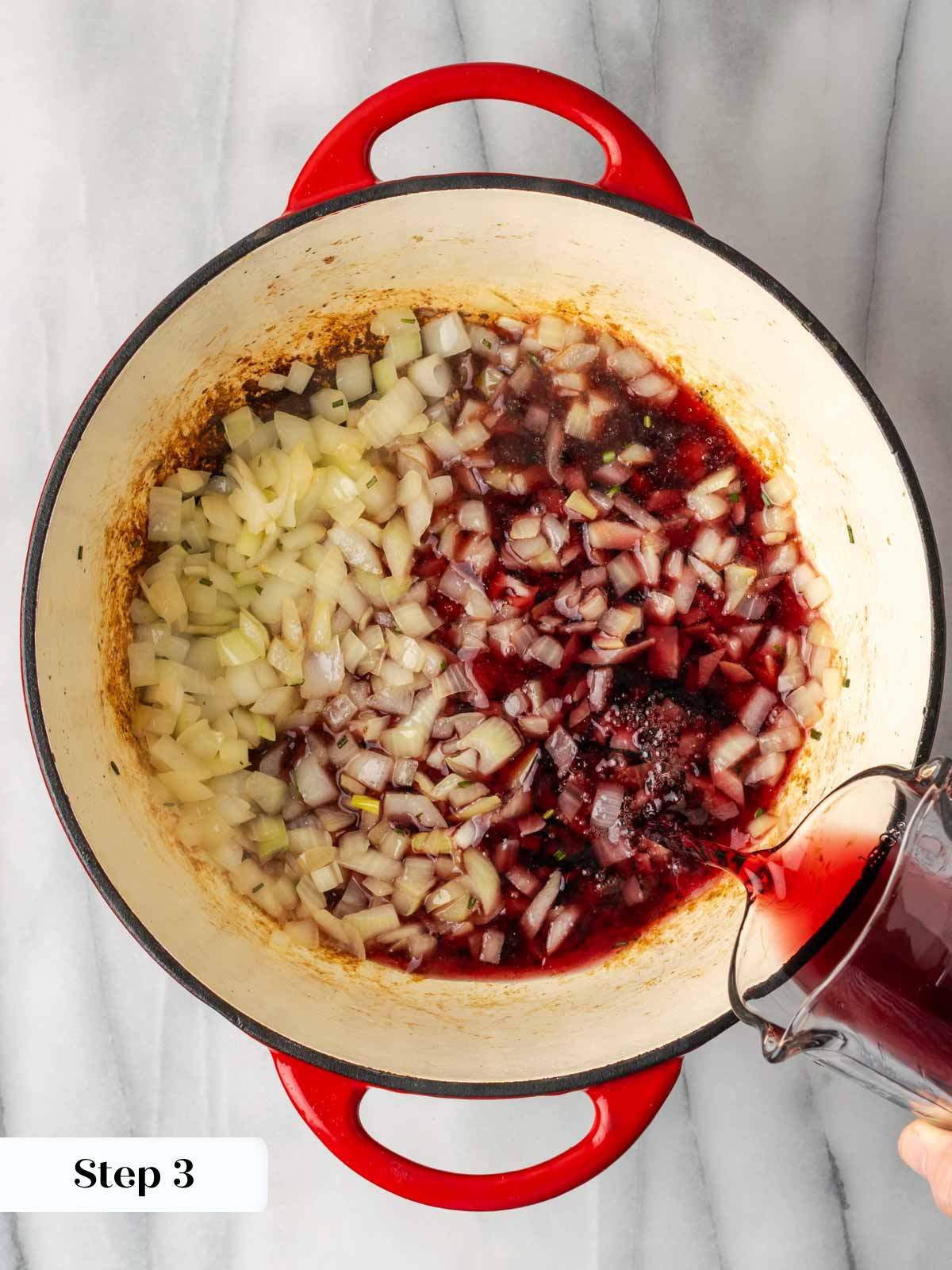 adding red wine to chili pot.