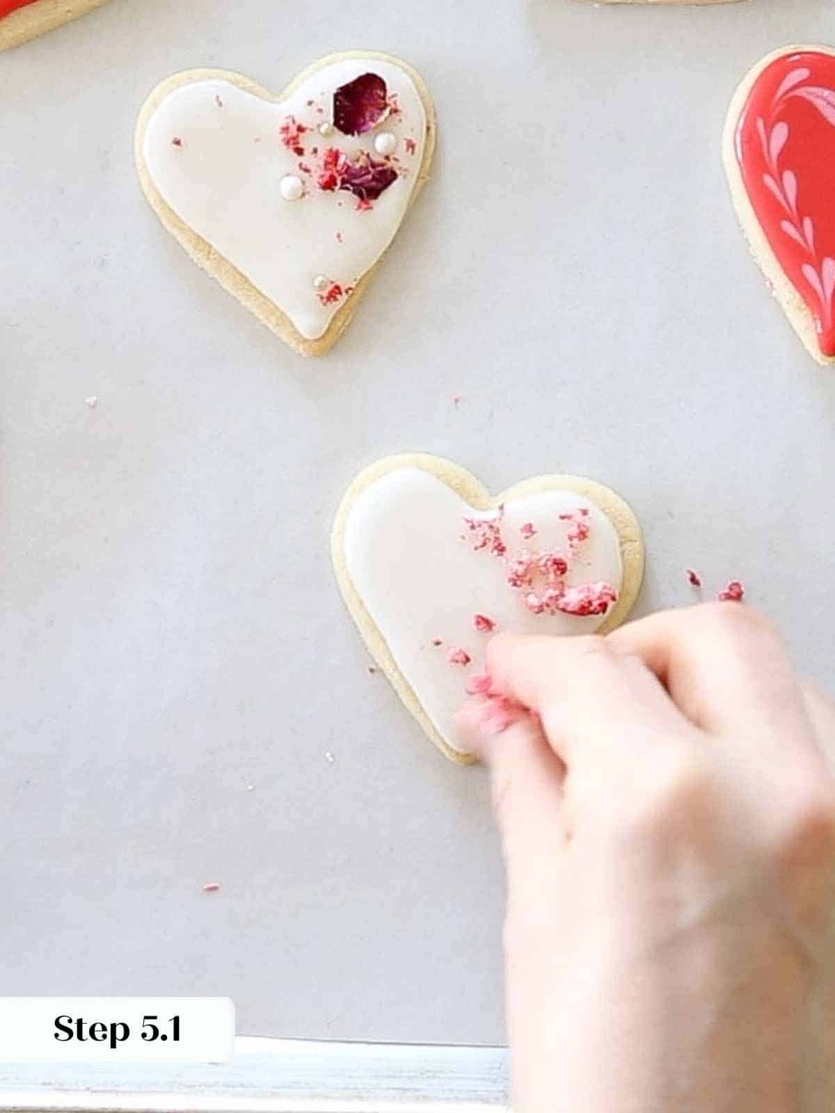 sprinkling dehydrated strawberries on white hearts.