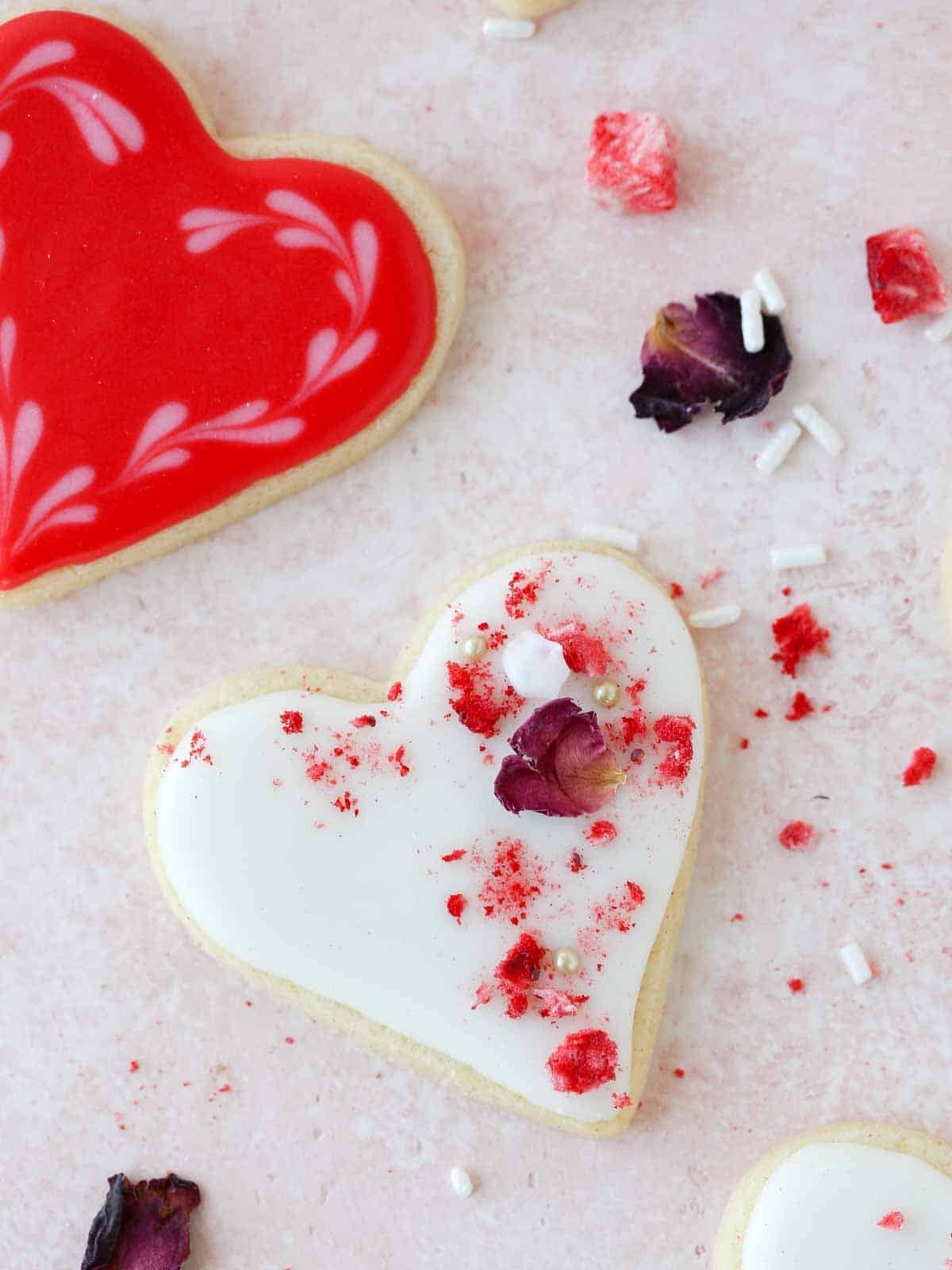 decorated heart sugar cookies on pink background.