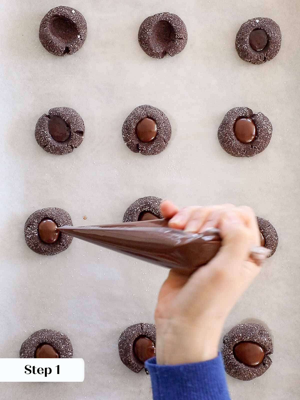 filling baked chocolate thumbprints with ganache.