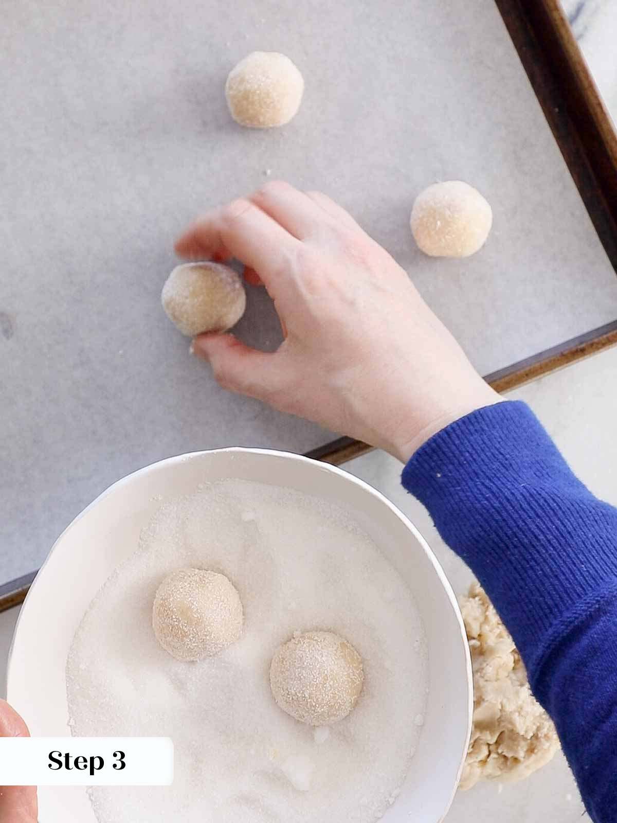 rolling dough in sugar them placing on baking sheet.