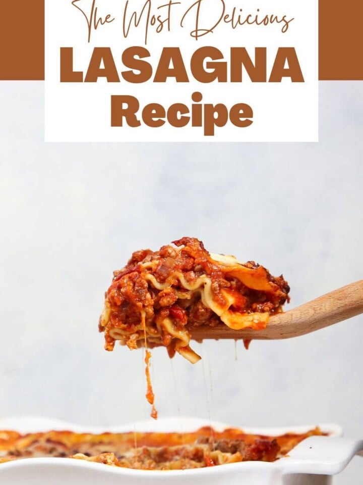 lasagna slice with cheese pulling above white baking dish.