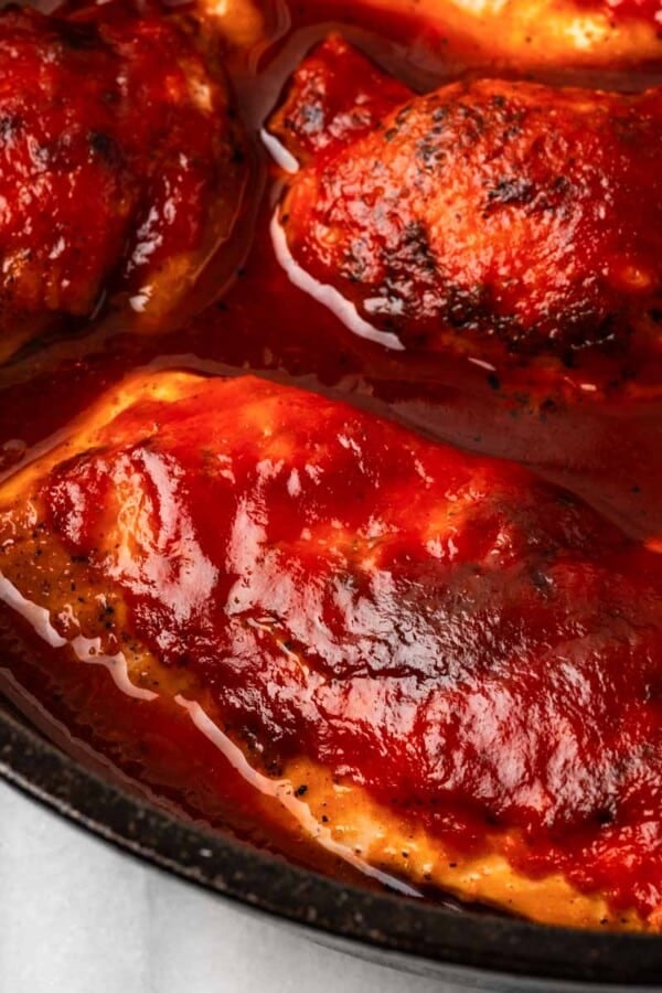 cooked bbq chicken breast in skillet.