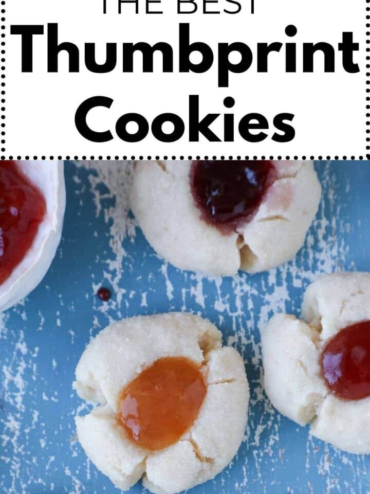 thumbprint cookies on blue board with different fillings and text.