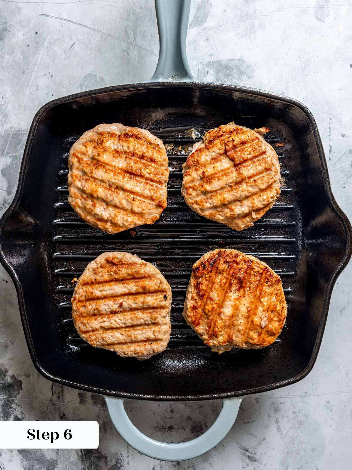 4 turkey burgers cooking in grill pan.
