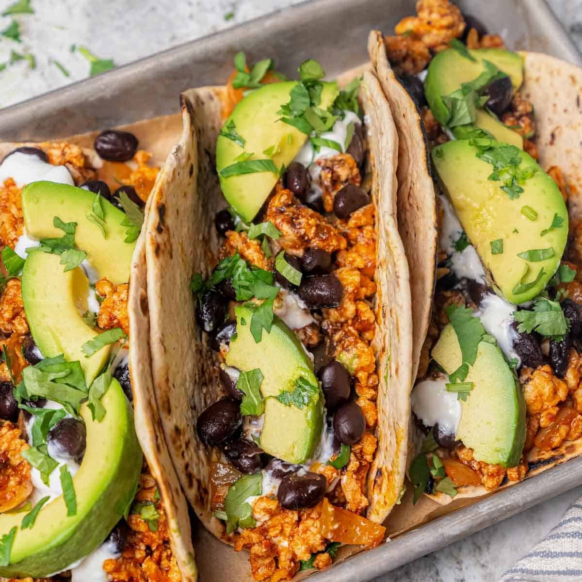 flavorful chicken taco with avocado and chopped cilantro.