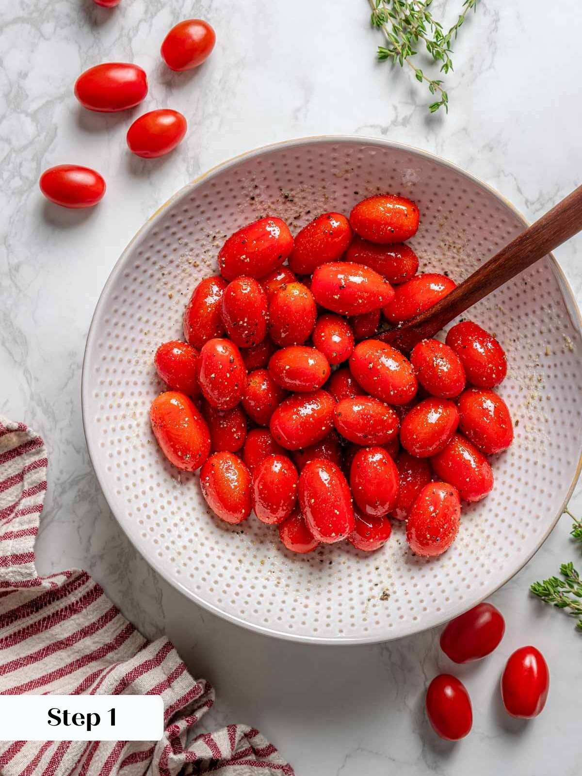 cherry tomatoes in bowl with oil and seasoning.