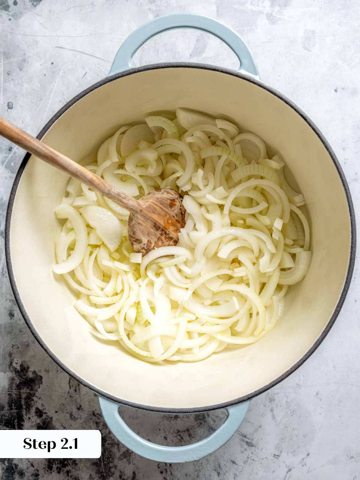 onions in dutch oven with wooden spoon.