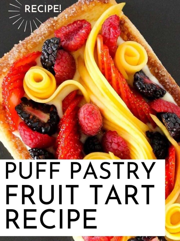 ornate puff pastry fruit tart on black plate with writing.