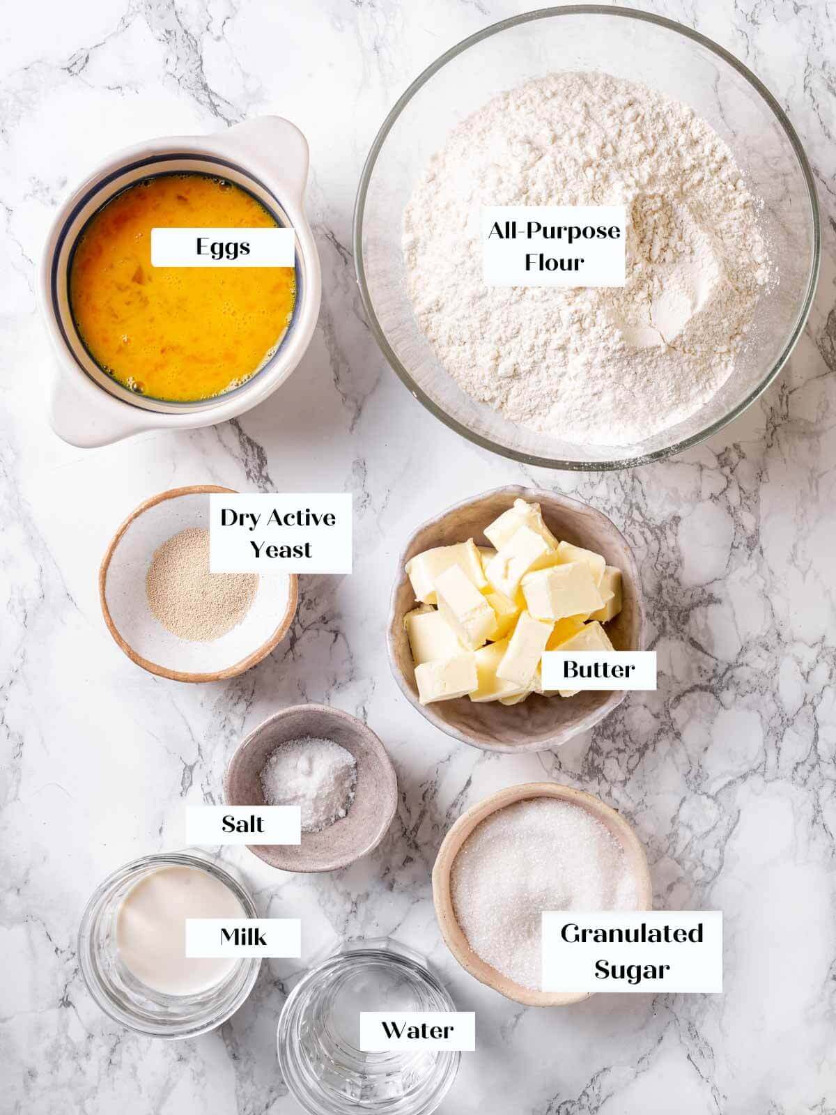 Brioche bread ingredients arranged on a white marble countertop.