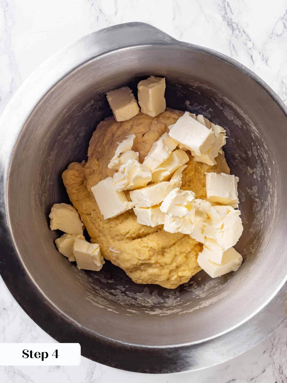 Adding softened butter to the brioche dough.