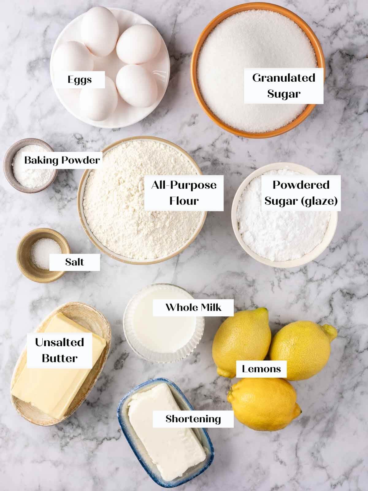 Lemon pound cake ingredients laid out on a white marble countertop.